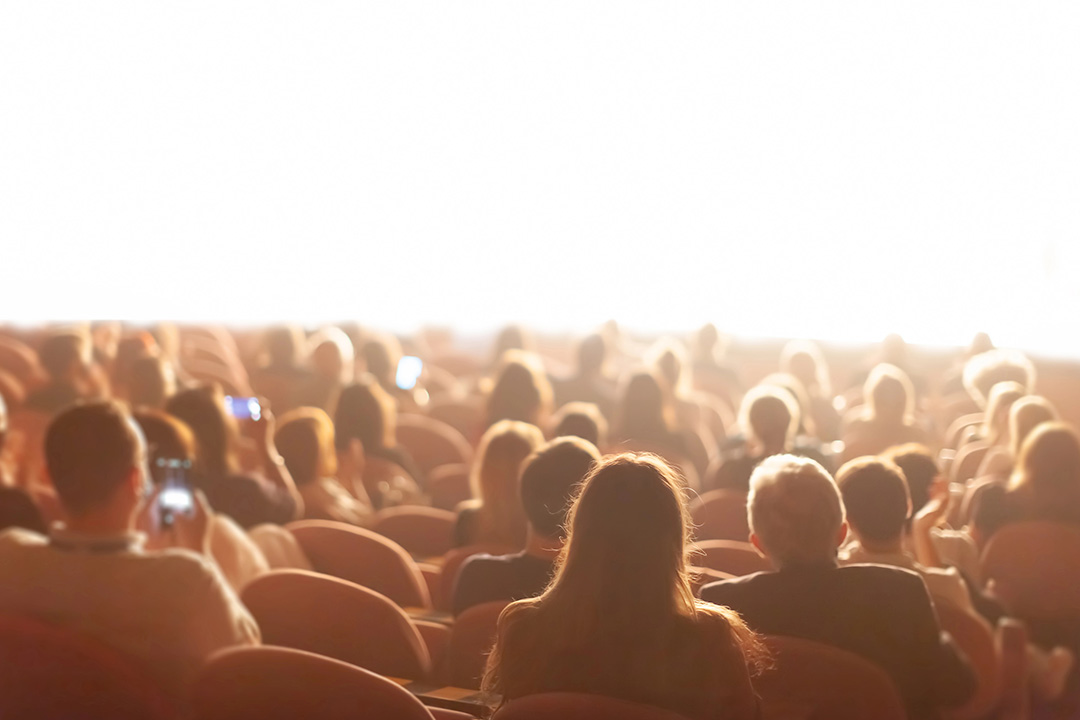 An image depicting an audience inside if a movie theater who is watching a film premier