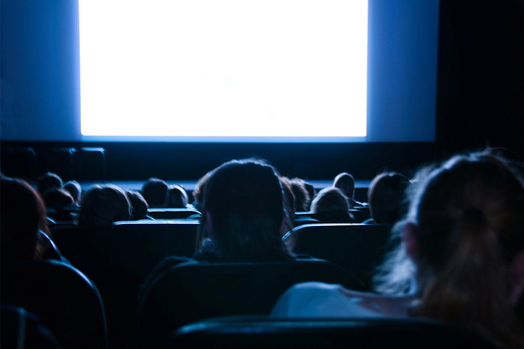 Audience watching a film in a dark theater, reflecting the fading glory of theatrical releases.