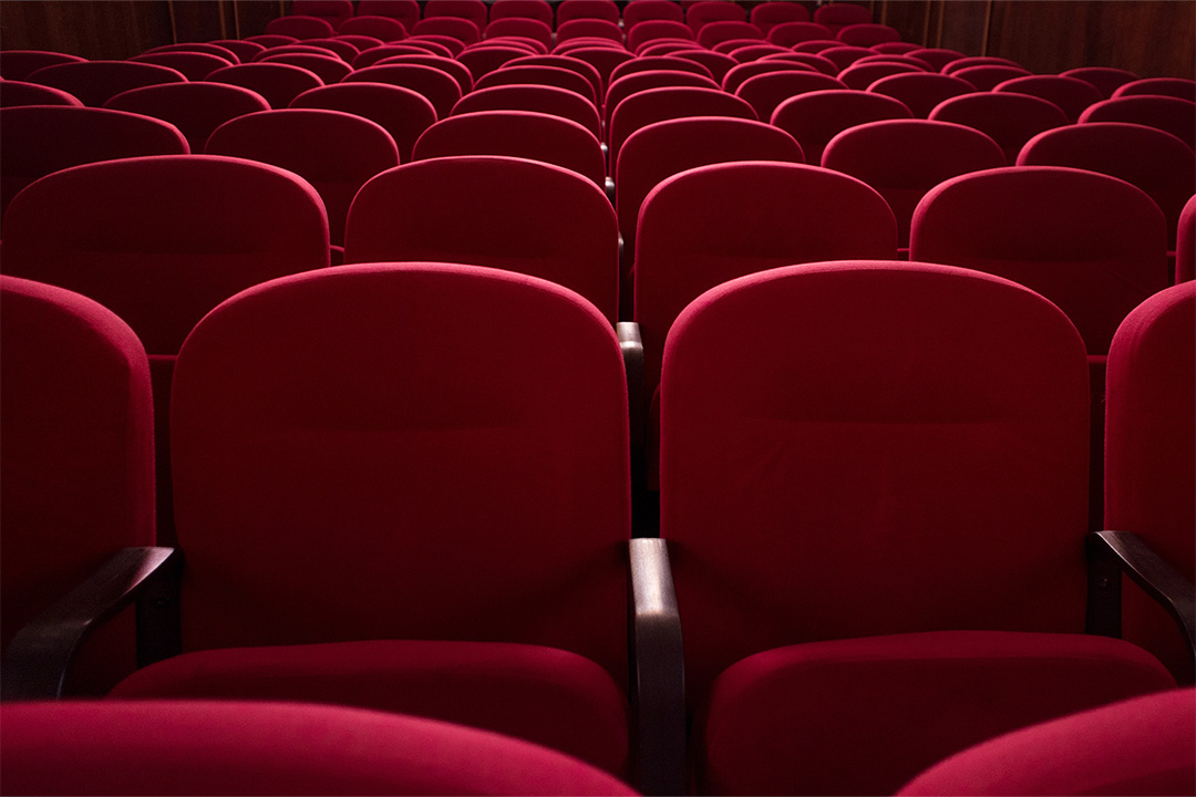 Rows of empty red theater seats representing the decline of traditional distribution.