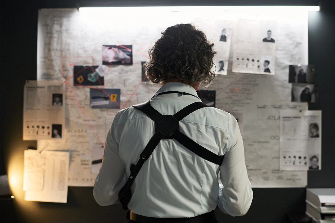 Individual studying a chaotic wall of notes, symbolizing the complexities of indie film distribution.