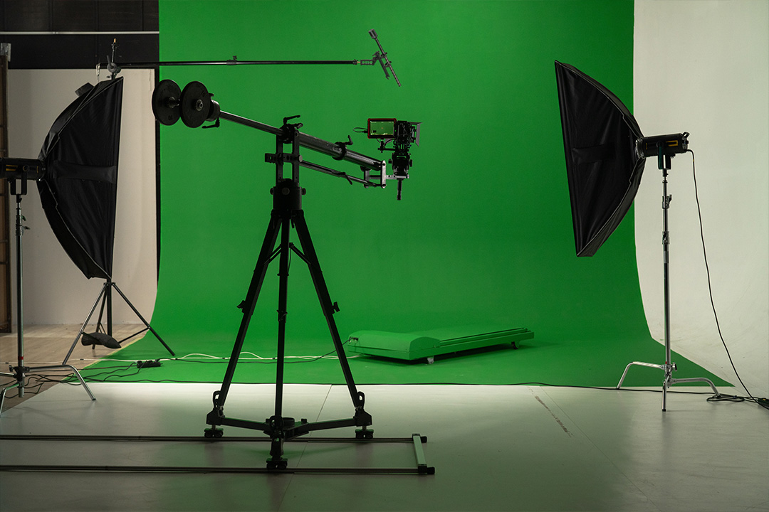 Professional green screen setup with camera and lighting equipment in studio.