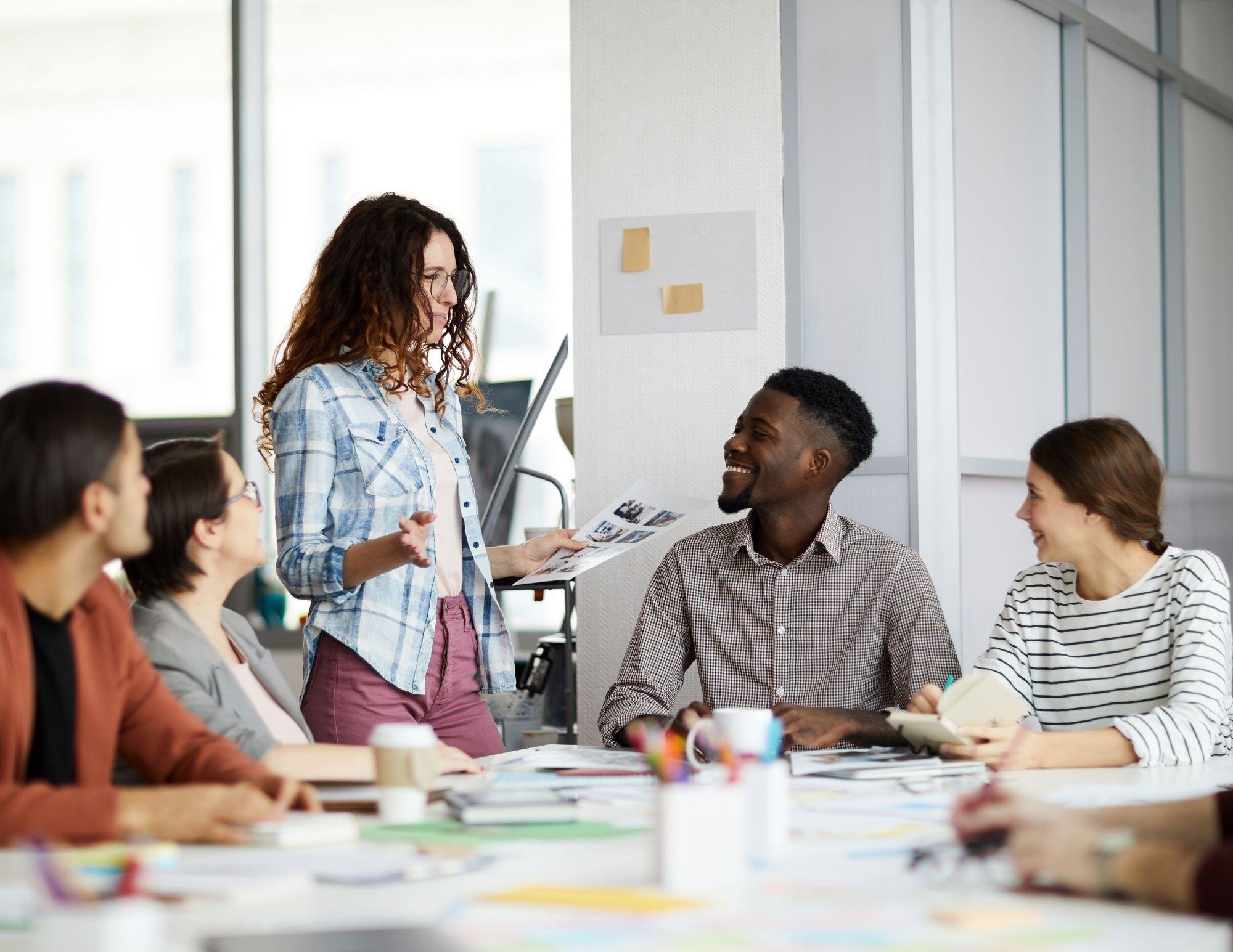 A diverse marketing team collaborates in a modern office setting, brainstorming and organizing cross-functional response teams. Team members are seen discussing strategies, writing on a whiteboard, and using laptops to coordinate efforts. The image highlights teamwork, communication, and adaptability in addressing dynamic marketing challenges.