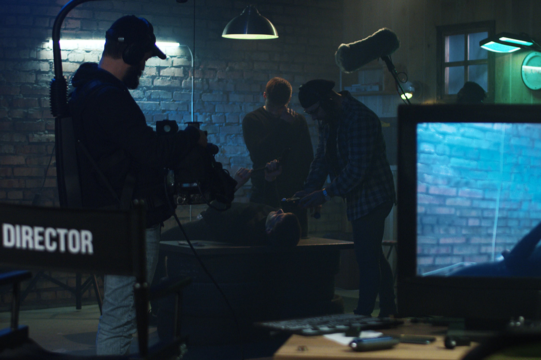  Crew working behind-the-scenes on a professional film set surrounded by studio lights.