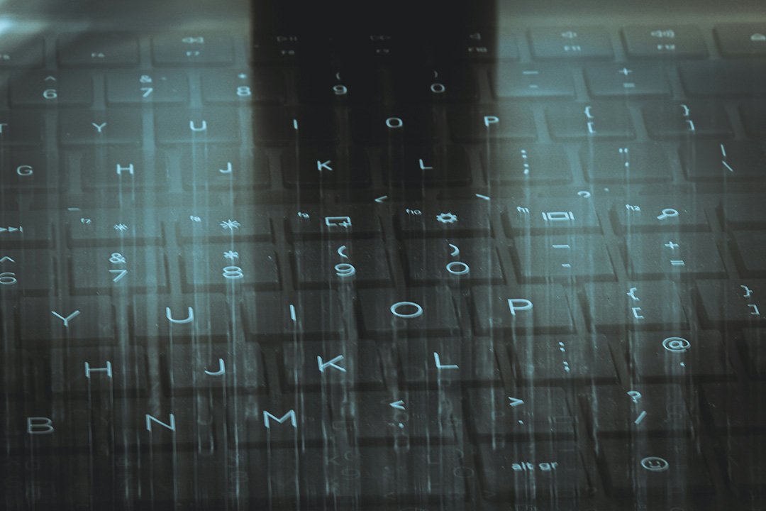 Blurred close-up of a black keyboard overlaid with flowing digital characters, symbolizing data, code, or digital advertising technology.