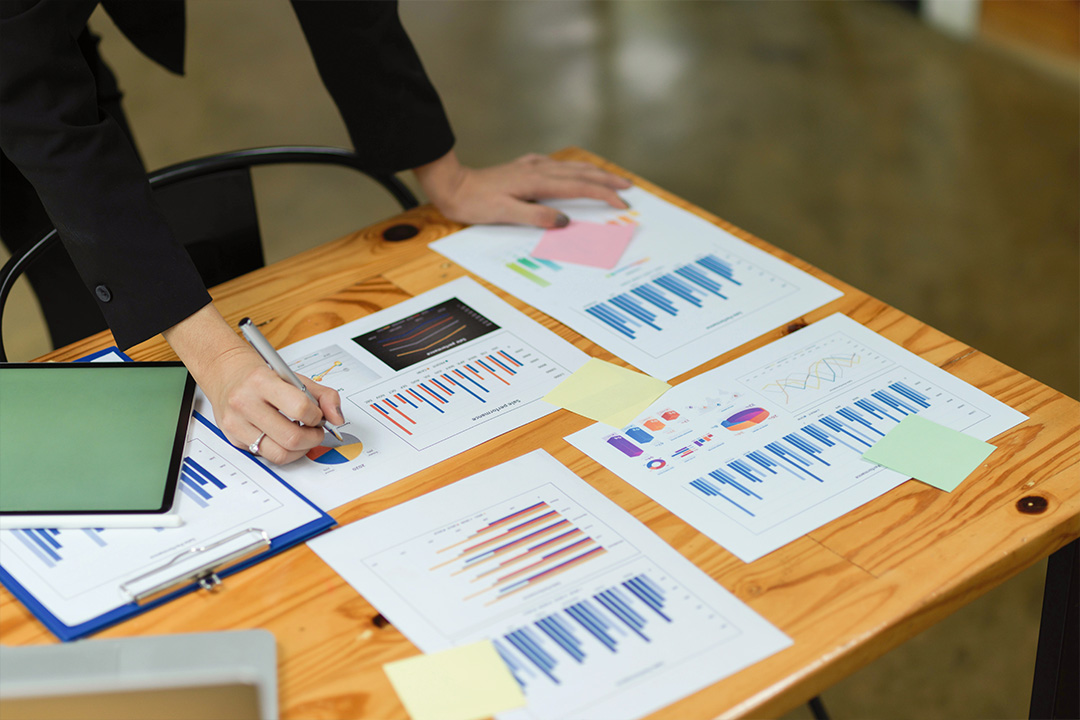 Close-up of hands reviewing audience data reports during a marketing strategy meeting.