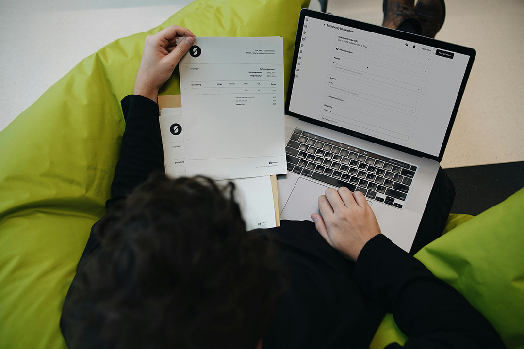An individual sitting with personal paperwork and a laptop representing the security and privacy of online transactions.