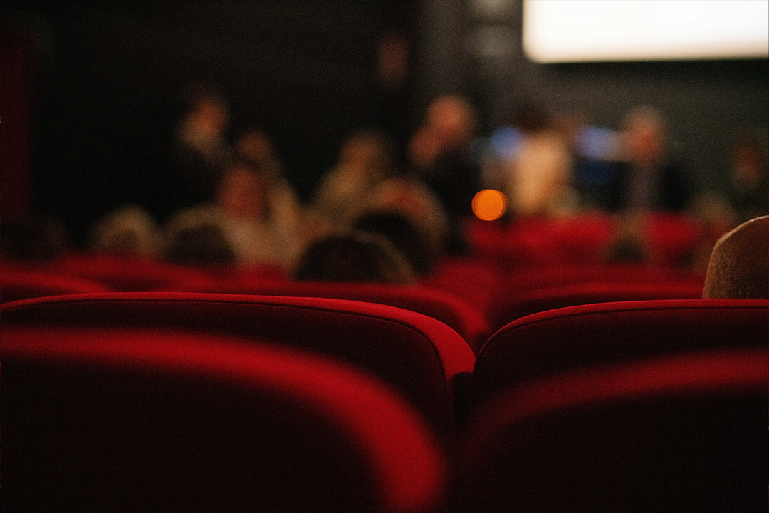 A blurred image depicting the inside of a movie theater with an audience watching a film to represent film marketing after 72 hours.